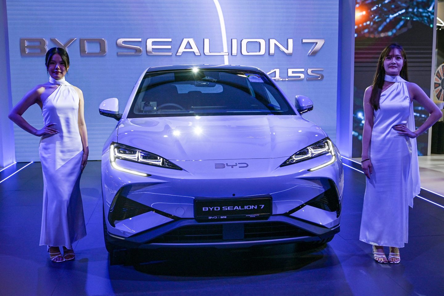 Models stand next to a BYD Sealion 7 electric vehicle (EV) by Chinese car manufacturer BYD on display at Singapore Motorshow in Singapore on January 9, 2025.