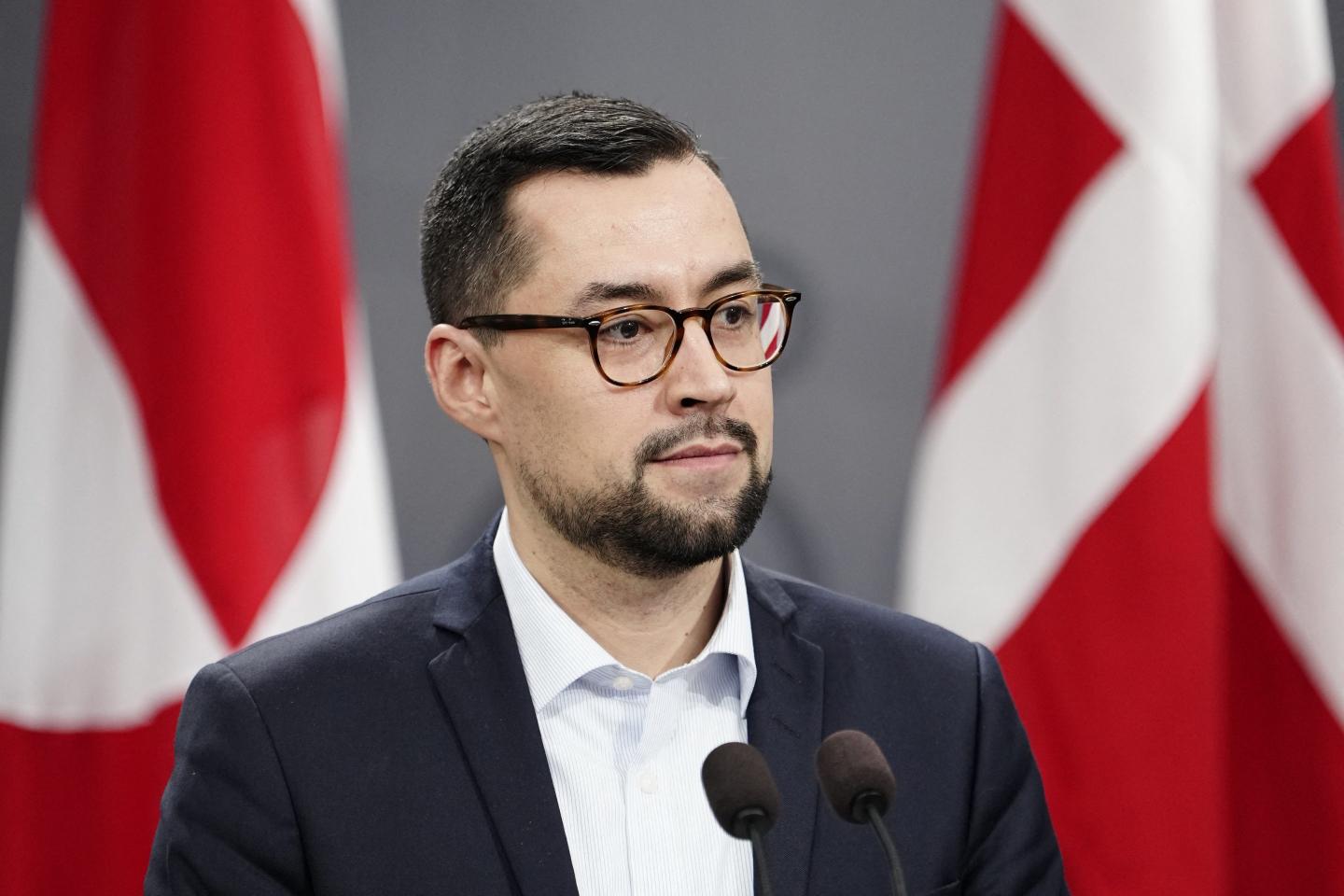 Greenlandic Prime Minister Mute Bourup Egede stands in front of two flags to give a speech