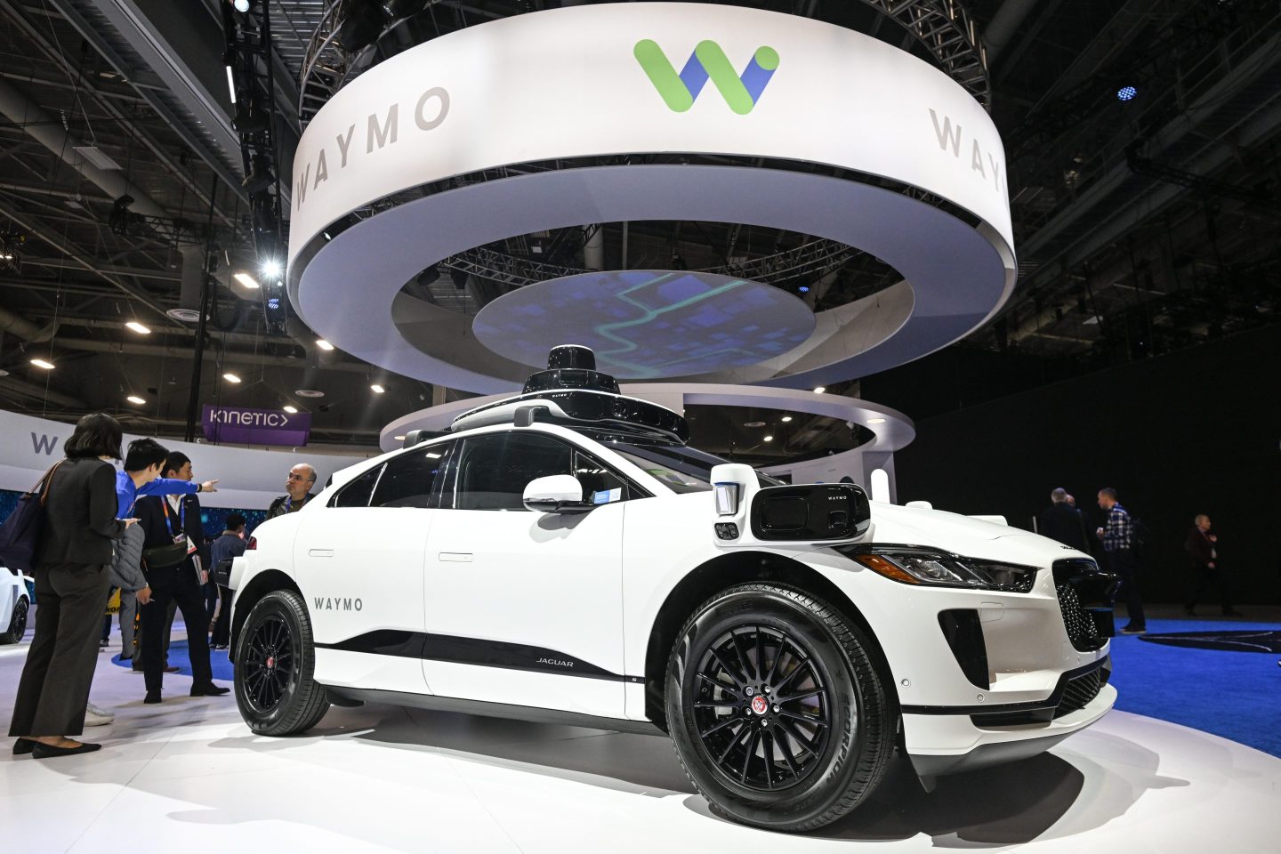 white car on display with a Waymo logo on the ceiling