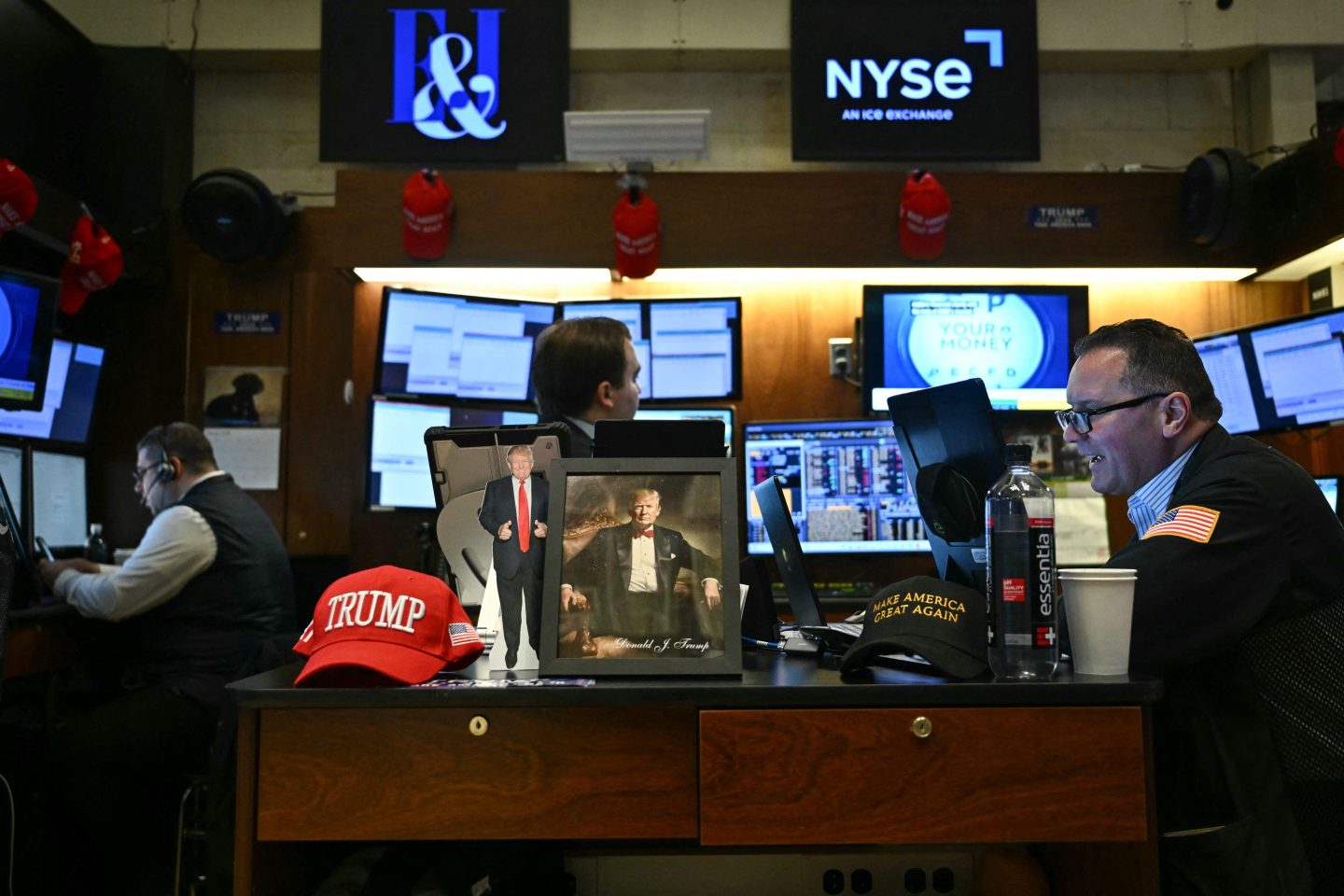 A photograph of US President Donald Trump sits on a desk as traders and financial professional work on the floor of the New York Stock Exchange at the opening bell on January 27, 2025 in New York City.