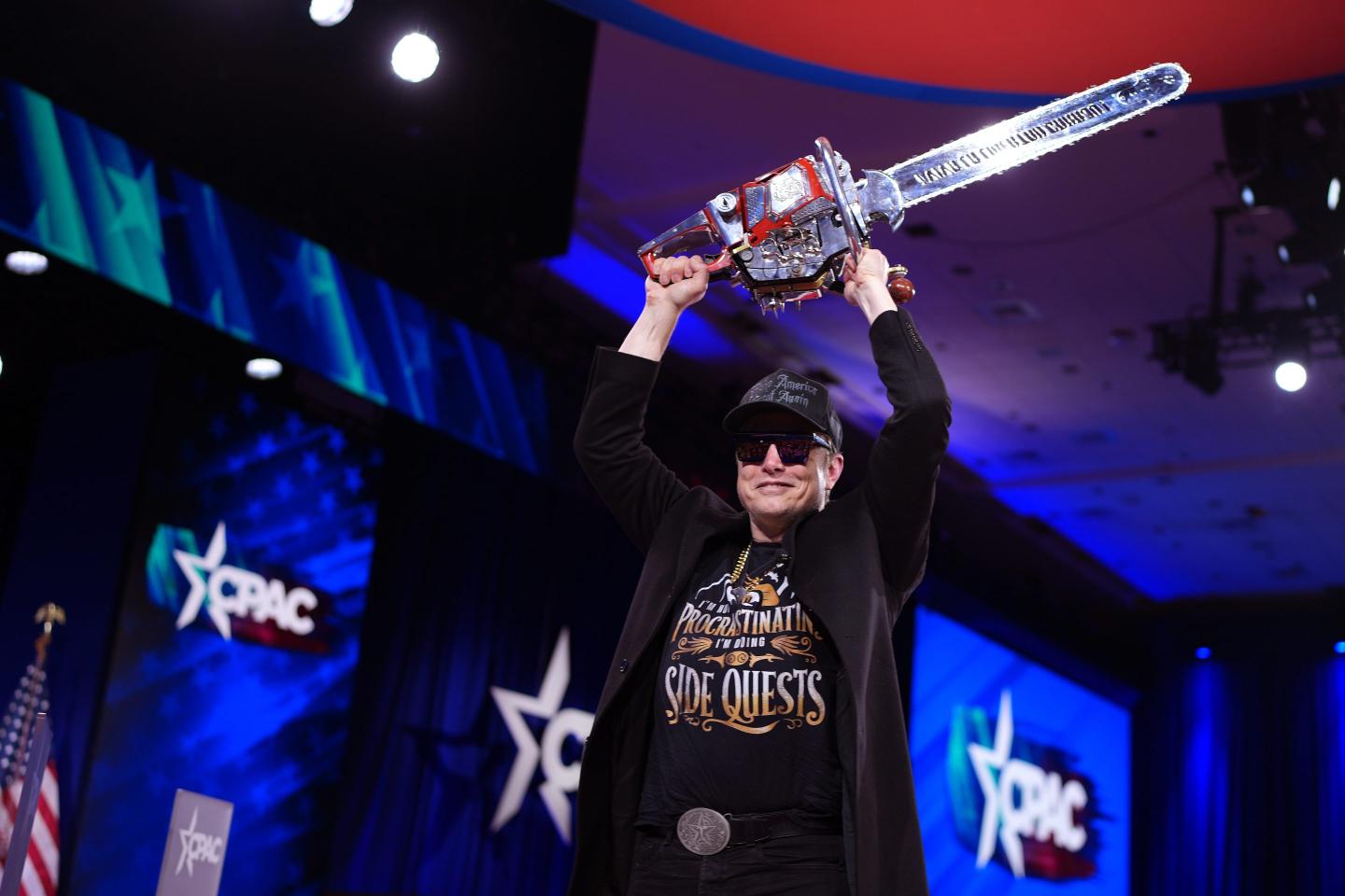 Elon Musk holding a chain saw