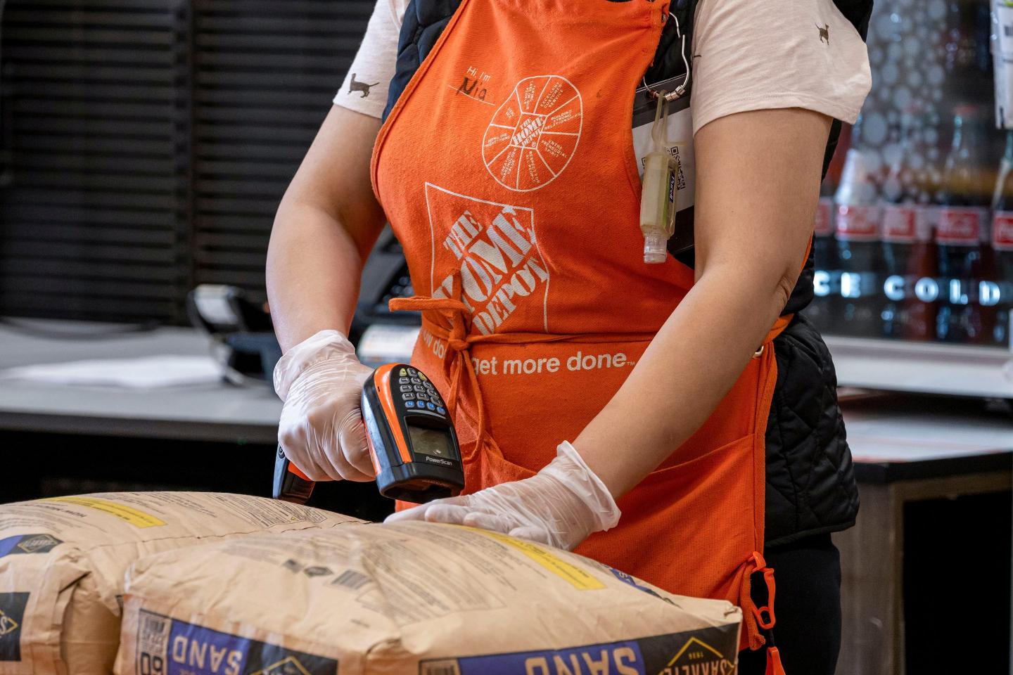 Worker in orange Home Depot apron scans a purchase