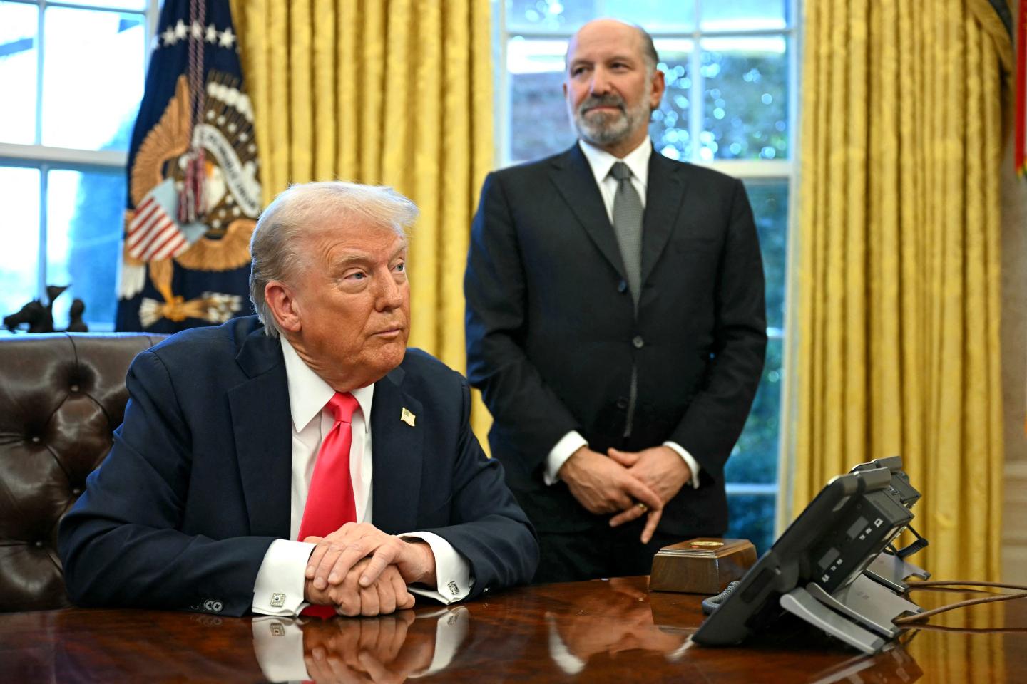 US President Donald Trump speaks to the press after signing an Executive Order, alongside US Secretary of Commerce Howard Lutnick (R)