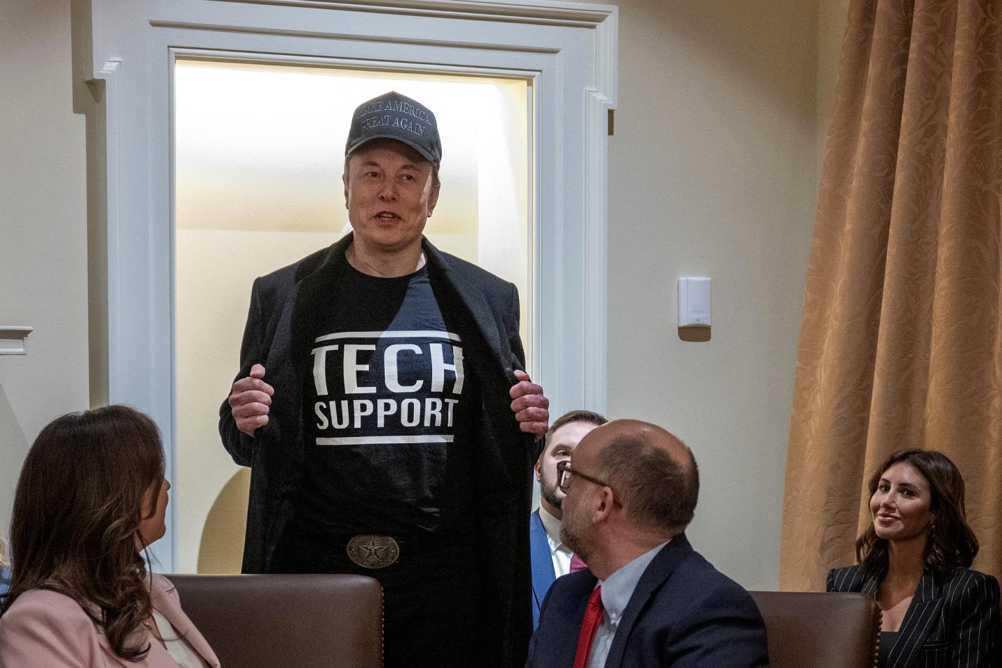 Elon Musk revealing a t-shirt that says "tech support."