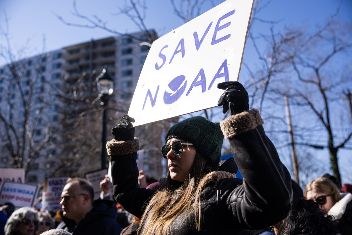 A woman holds up a sign that says "Save NOAA"