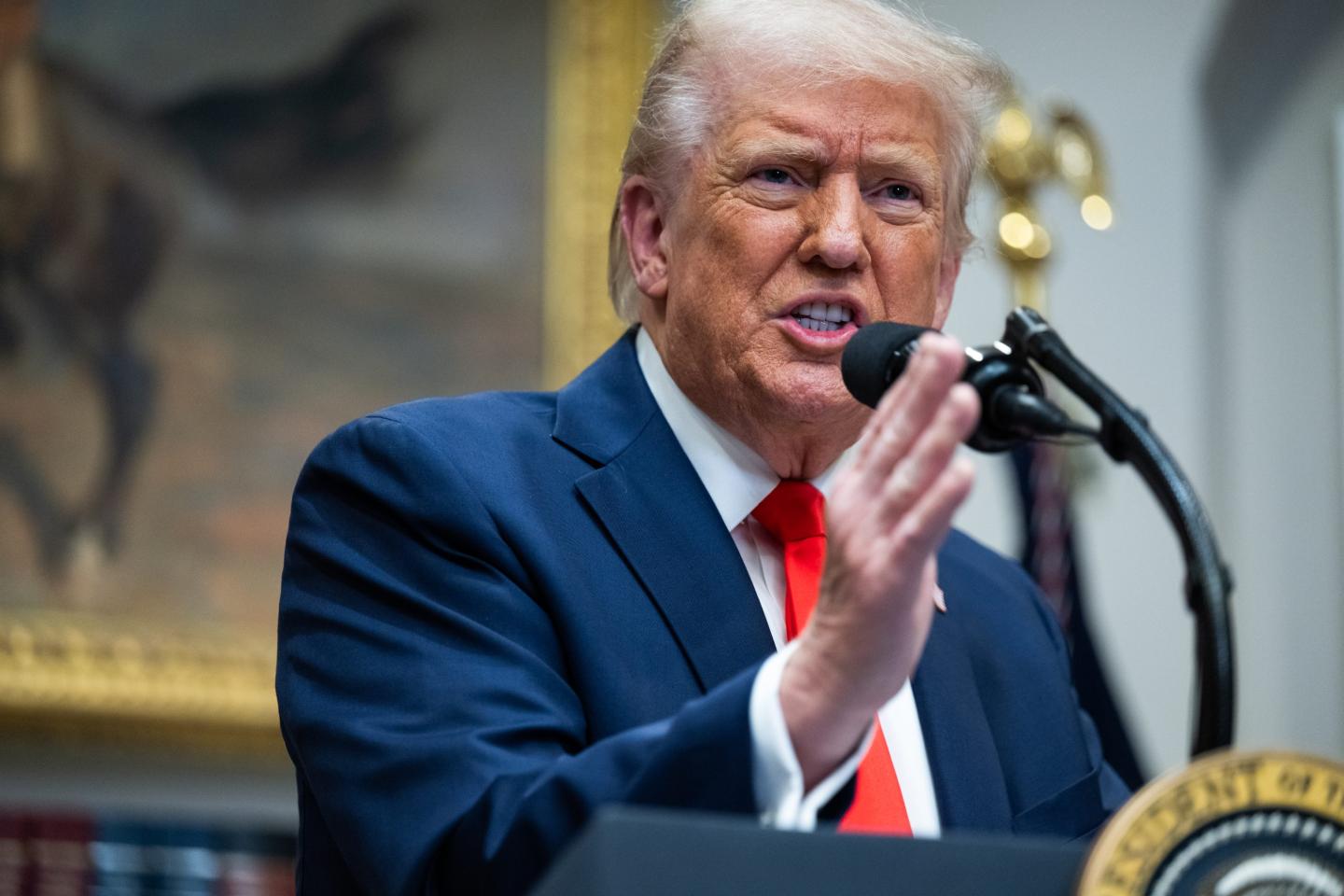 Donld Trump speaking into a microphone on a podium