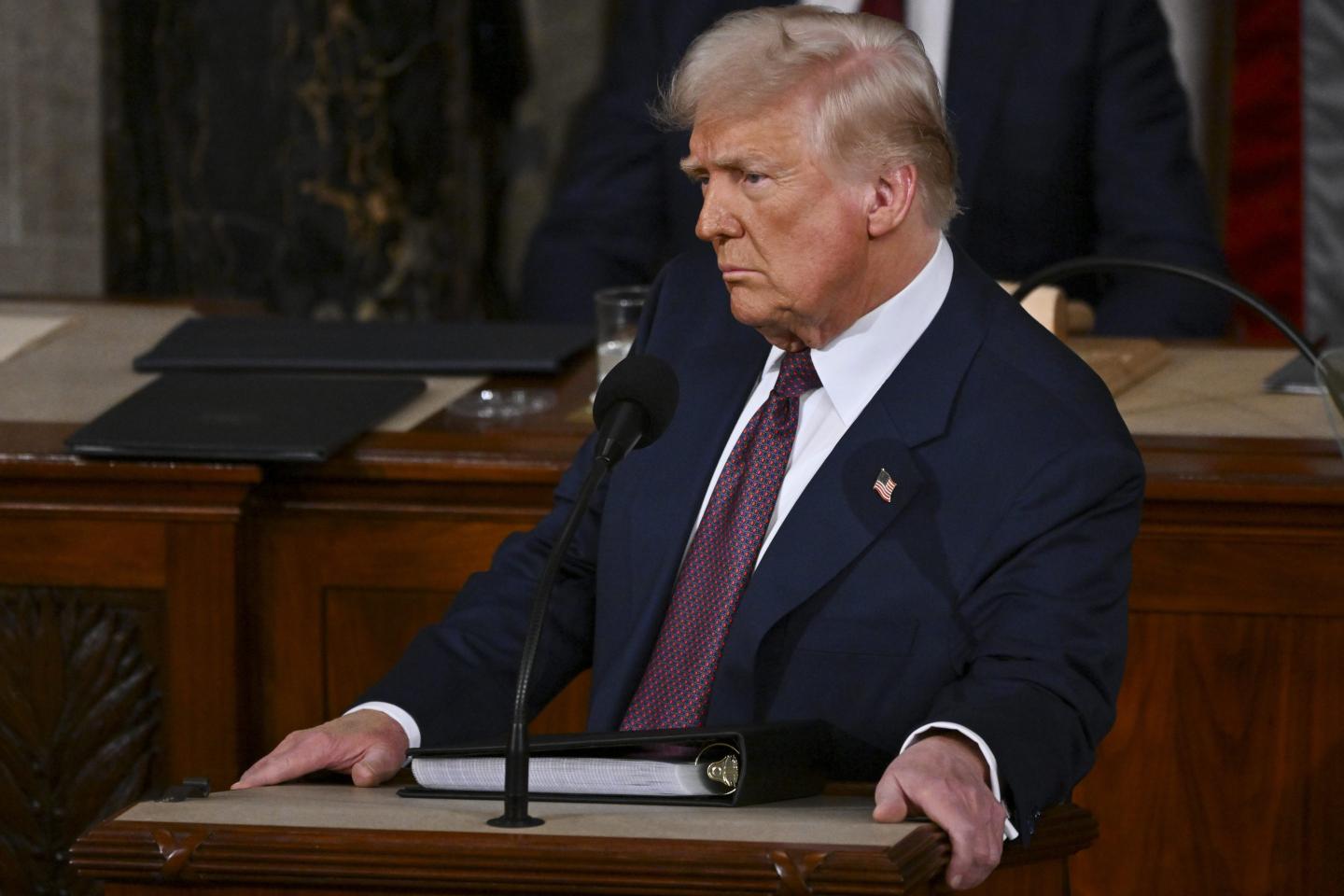 Donald Trump furrows his brow as he stands behind a podium in the Congressional chamber.