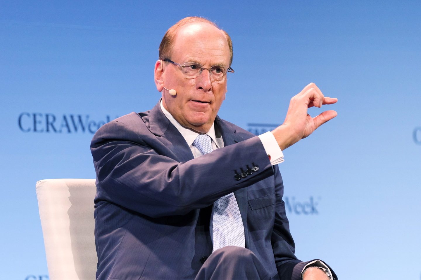 BlackRock CEO Larry Fink holds up two pinched fingers while speaking.