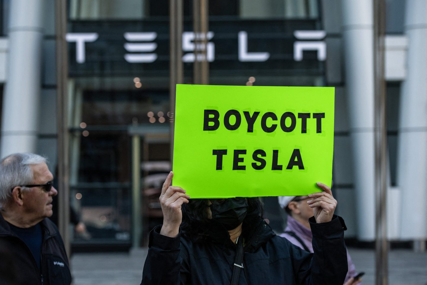 Protesters hold signs and sing chants during a protest against Elon Musk and his Tesla car company outside the Tesla dealership in Boston on March 15.