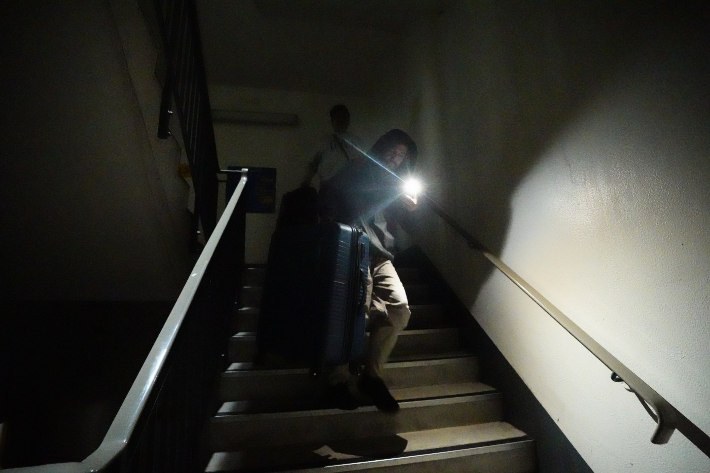 Stranded passengers makes their way down unlit stairs due to lifts not working to the car park at Heathrow Terminal 4 in London. More than 1,300 flights to and from Heathrow Airport will be disrupted on Friday due to the closure of the airport following a fire at the North Hyde electrical substation last night. Picture date: Friday March 21, 2025. (Photo by James Manning/PA Images via Getty Images)