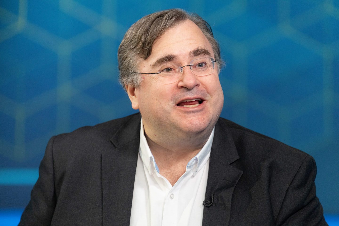 Reid Hoffman speaks in front of a patterned blue background.