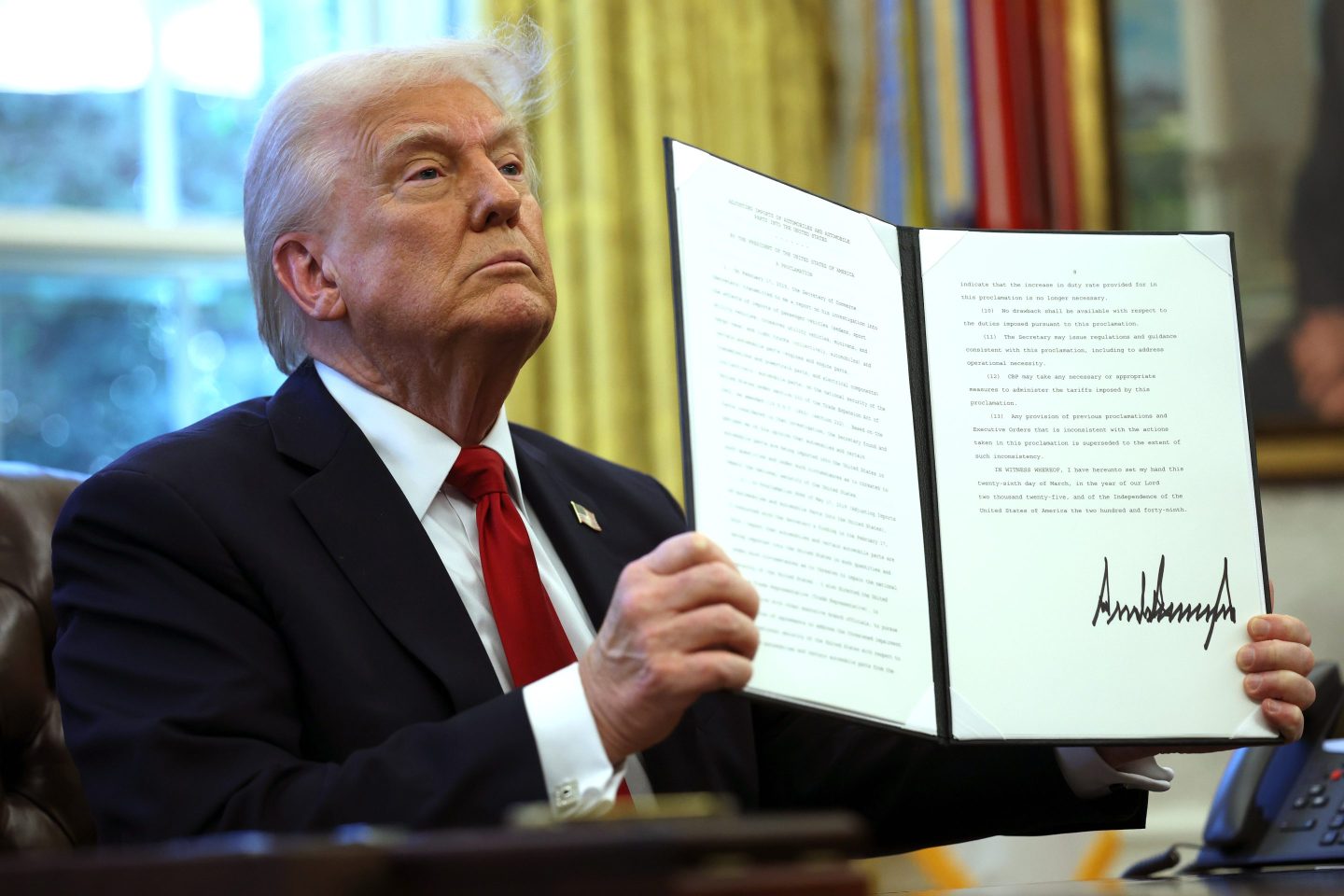 President Donald Trump displays a signed executive order in the Oval Office of the White House on March 26, 2025 in Washington, DC.