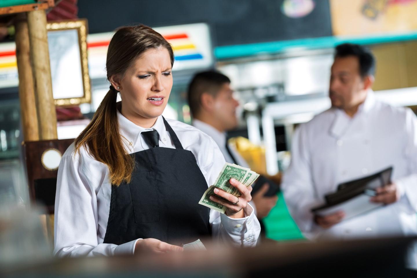 Woman disappointed holding just a few dollars.