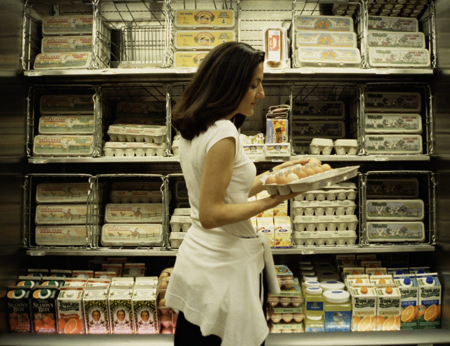 Woman in supermarket with a carton of eggs.