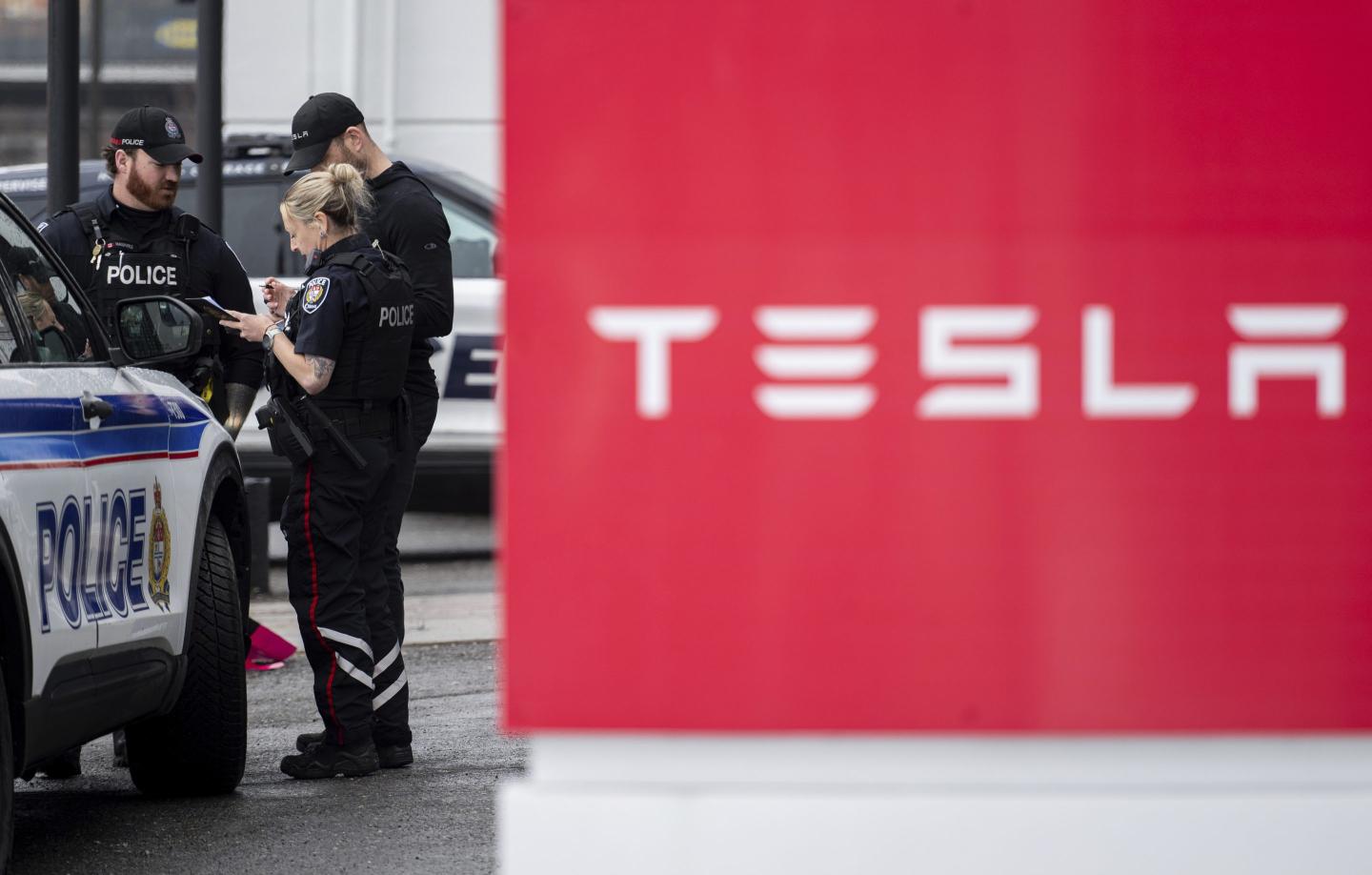 Police officers stand next to a Tesla sign