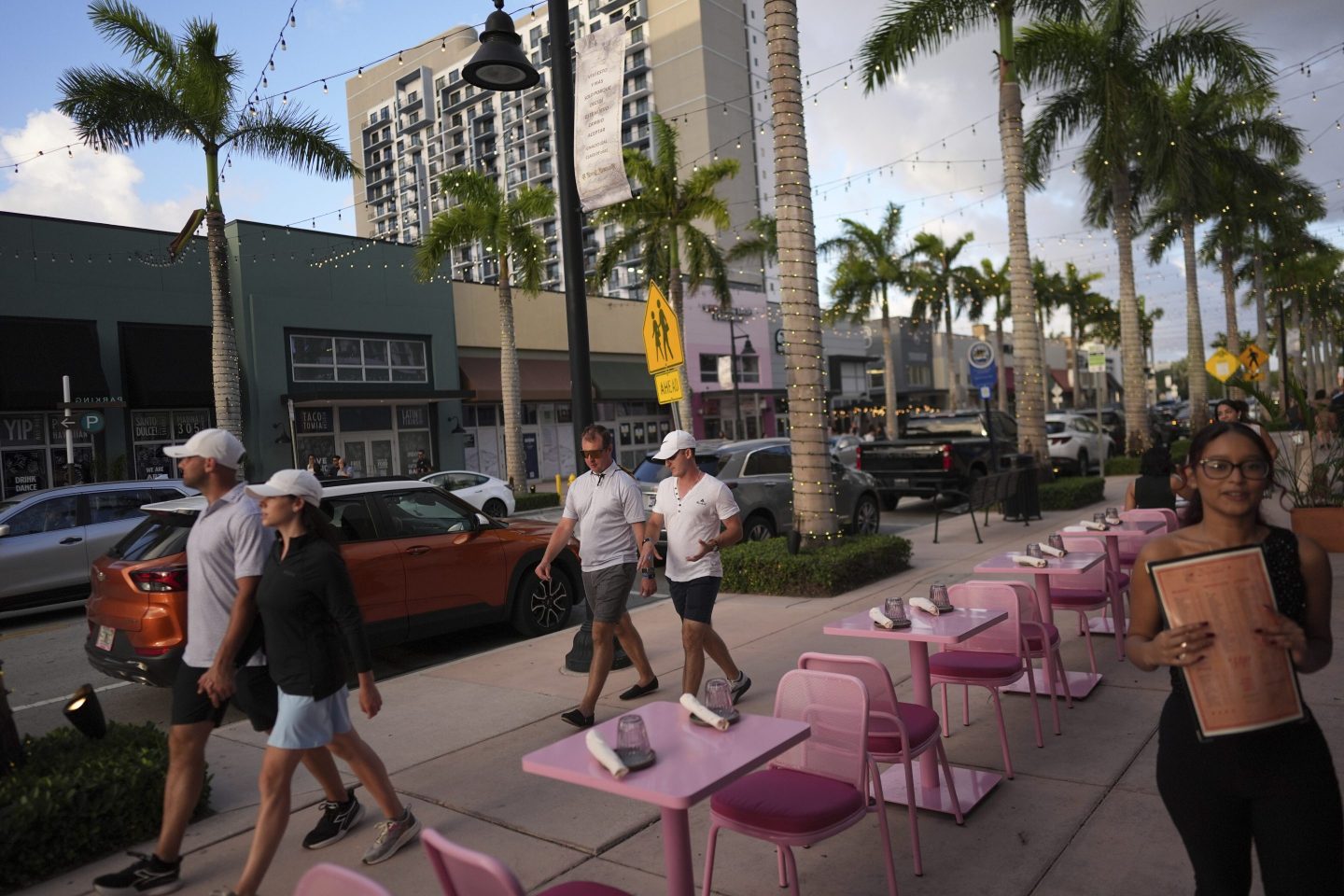 People walk along a street lined with restaurants and businesses in Doral, Fla., on April 5, 2025.