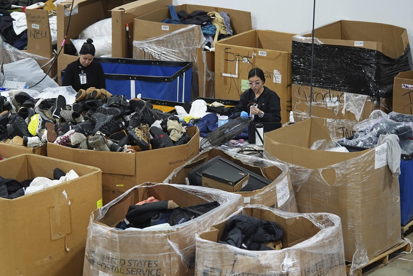 People work amid boxes of returned or overstocked clothing, shoes, boots, coats, packs and other items in Englewood, Colo., on April 17, 2025. 