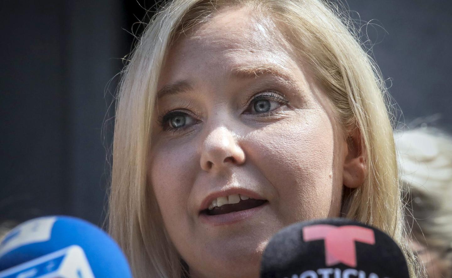 Virginia Giuffre speaks in front of microphones