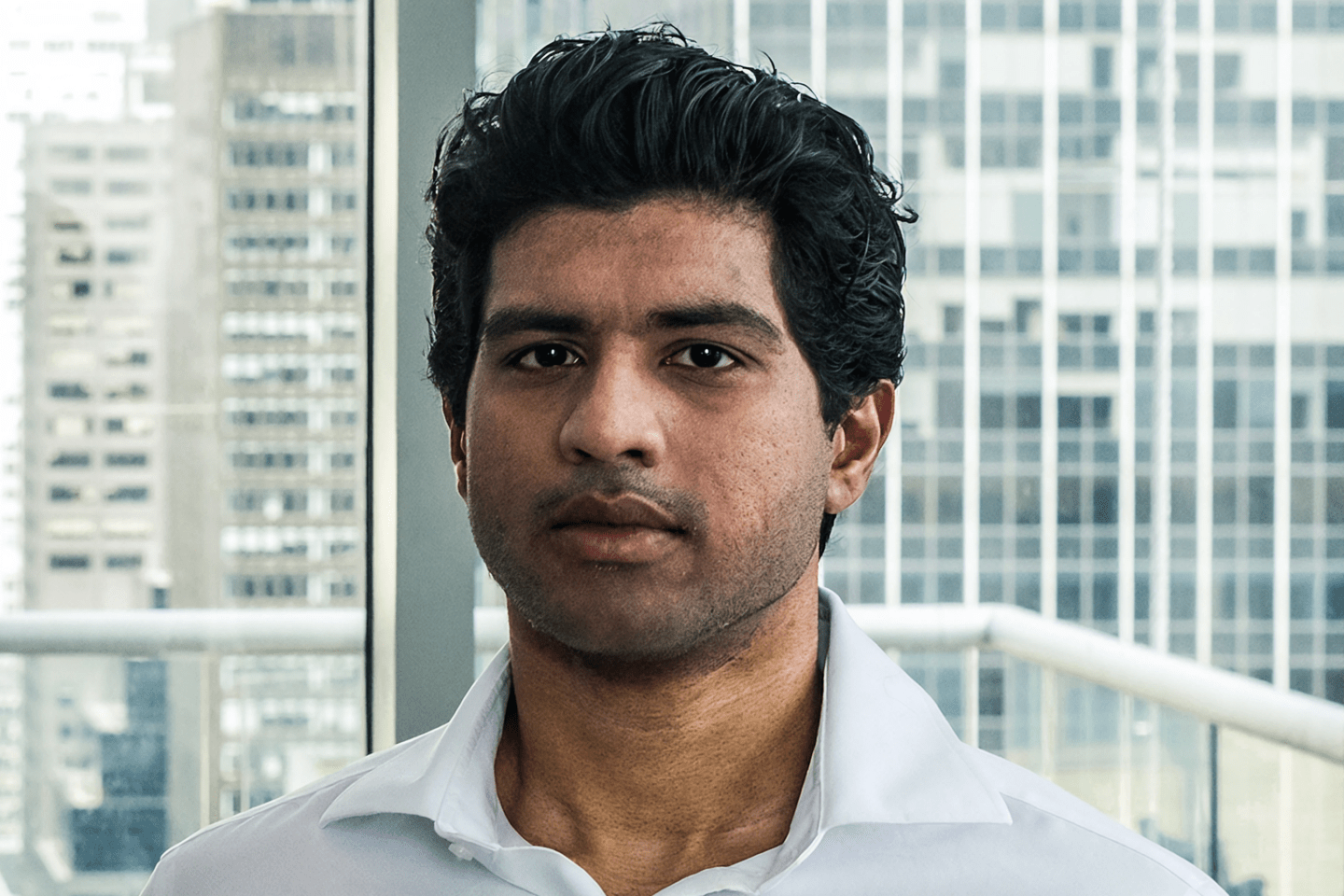 Abhi Pingle looks into the camera in front of an office window.