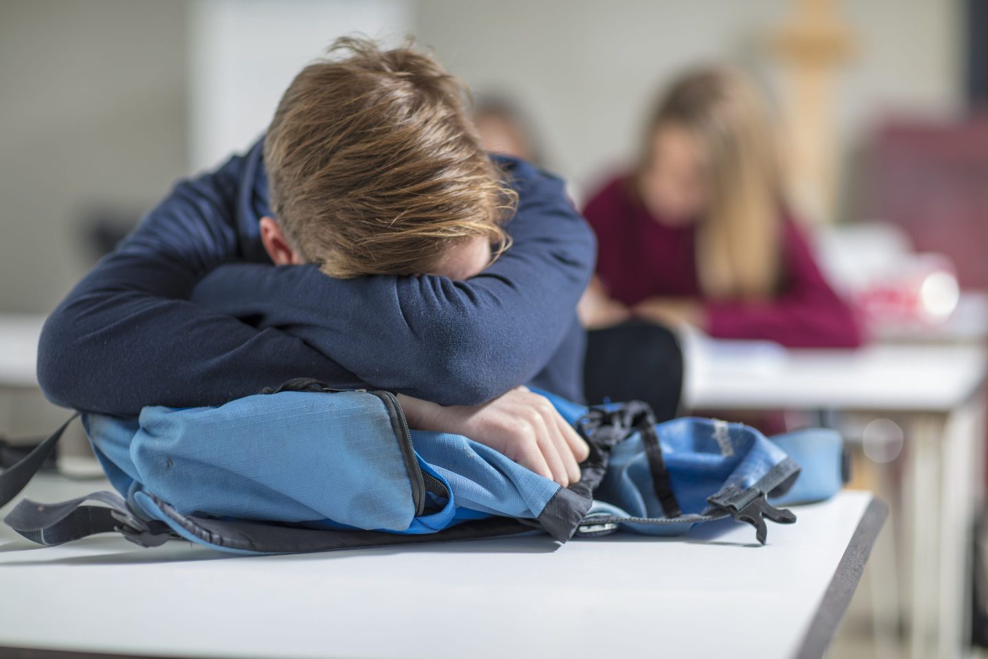 teenage boy with his head down on his desk