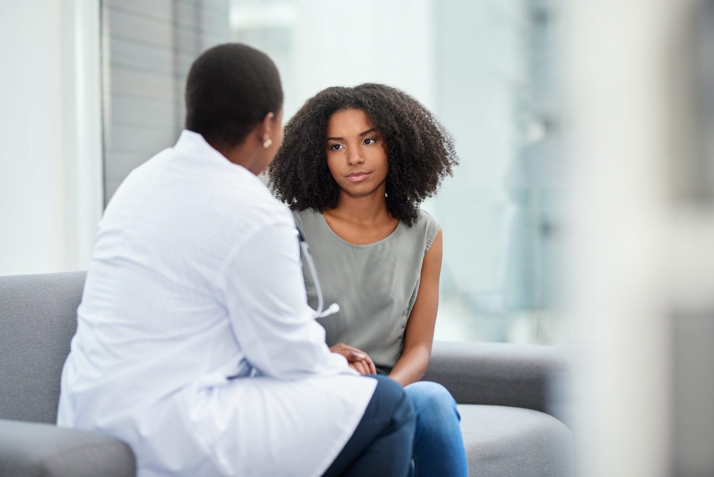 Young woman consulting with doctor whose back is to the camera