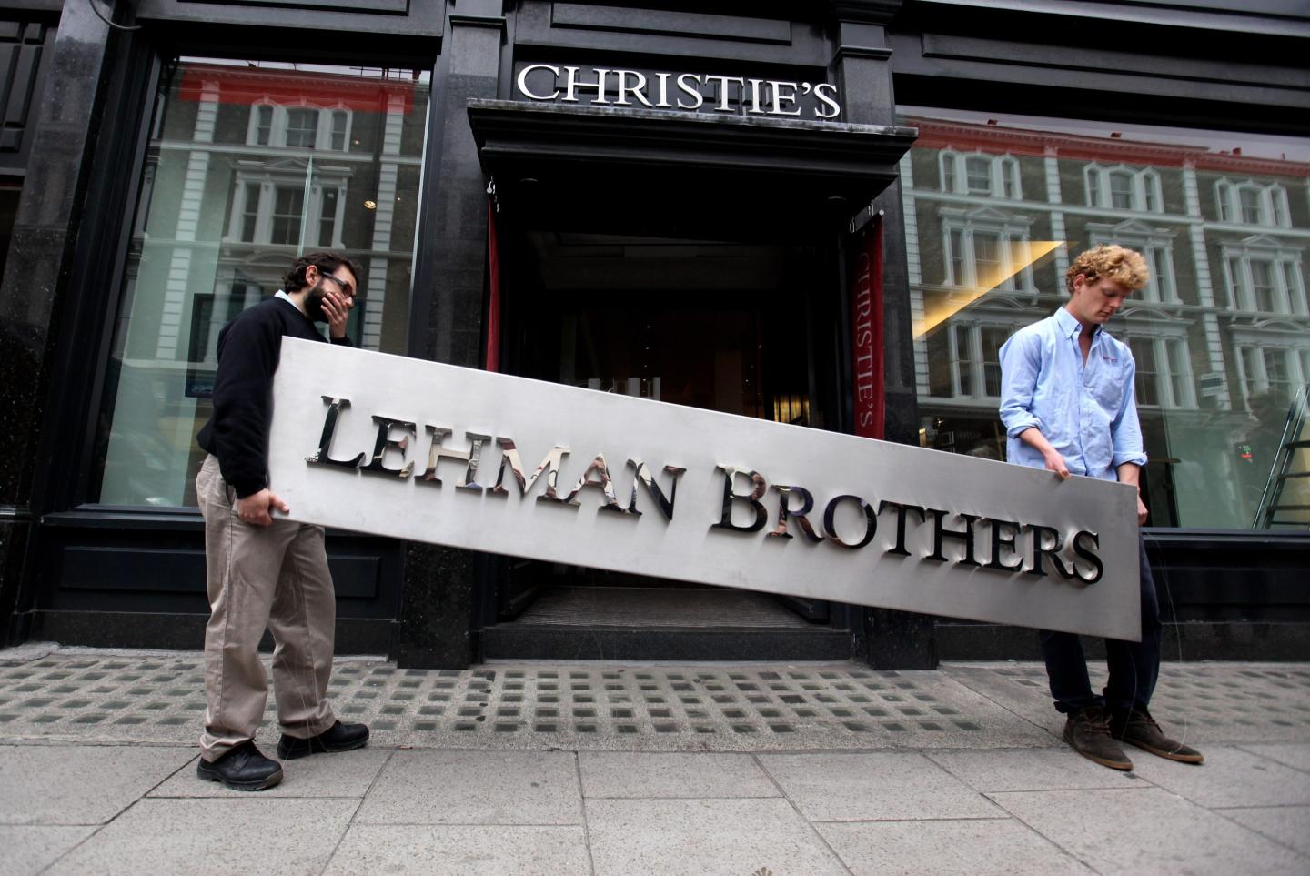 Two employees carry a Lehman Brothers sign in front of a Christie's auction house.