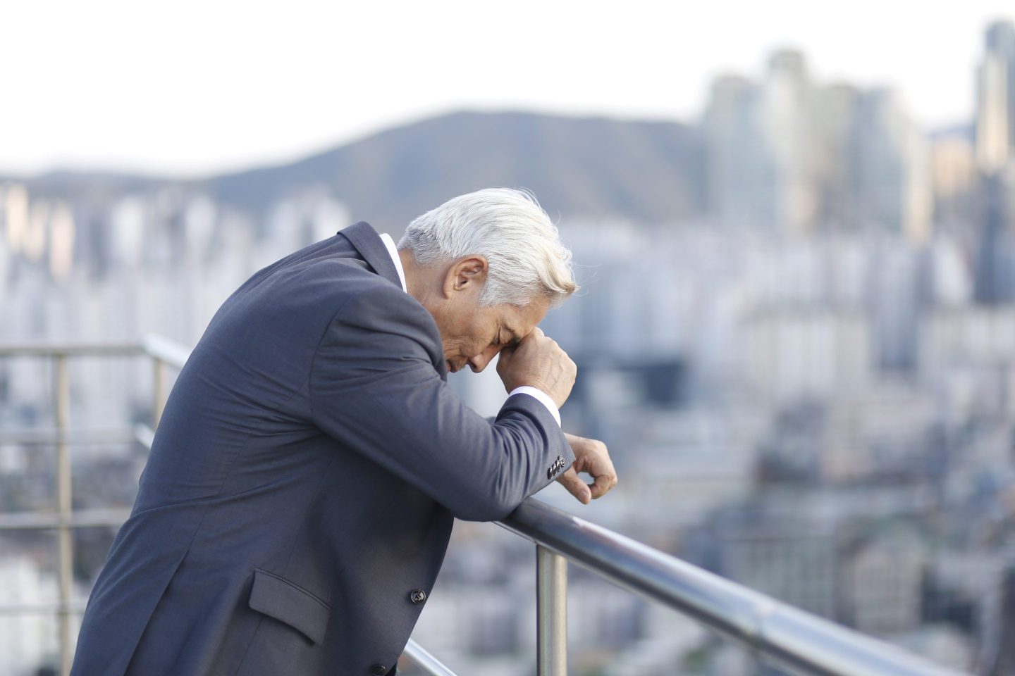 stressed business man leaning over balcony