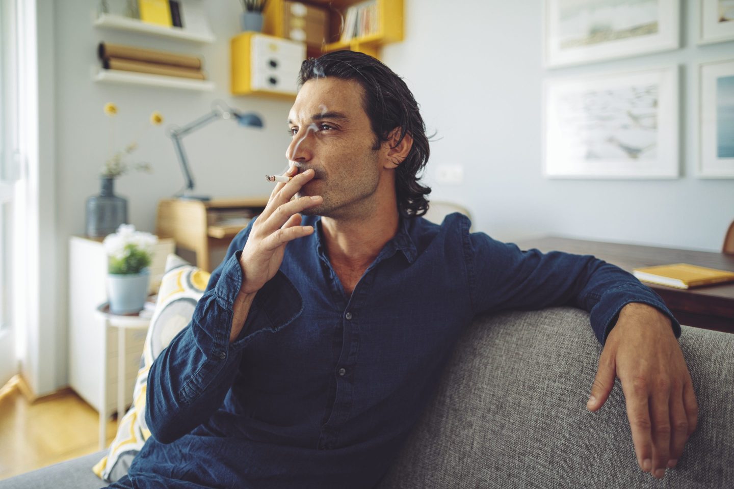 Young man on couch smoking a cigarette
