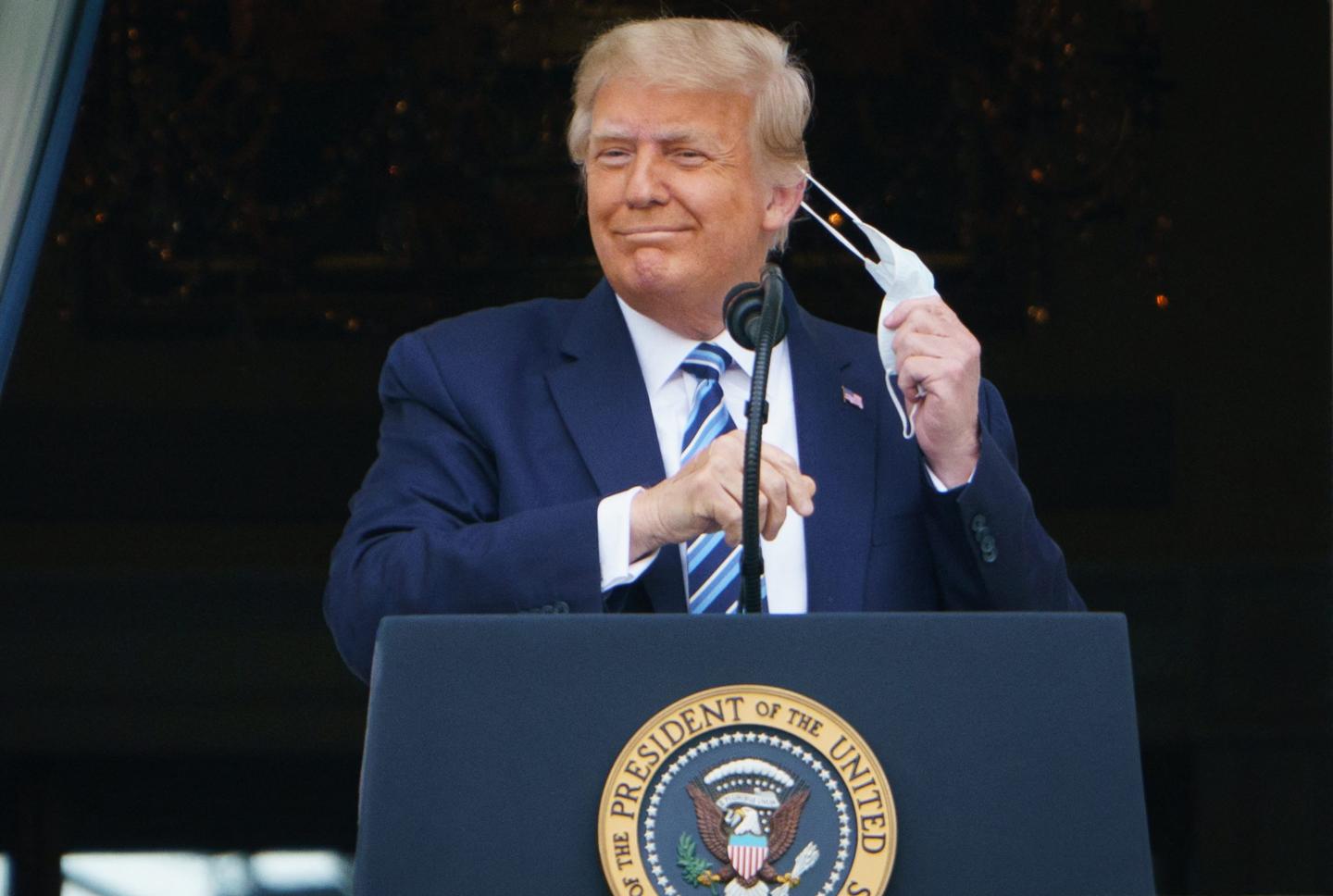 President Donald Trump takes his mask off