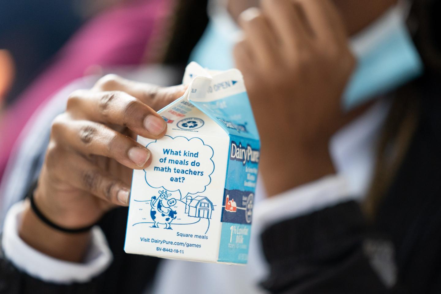 A young girl holds a carton of milk