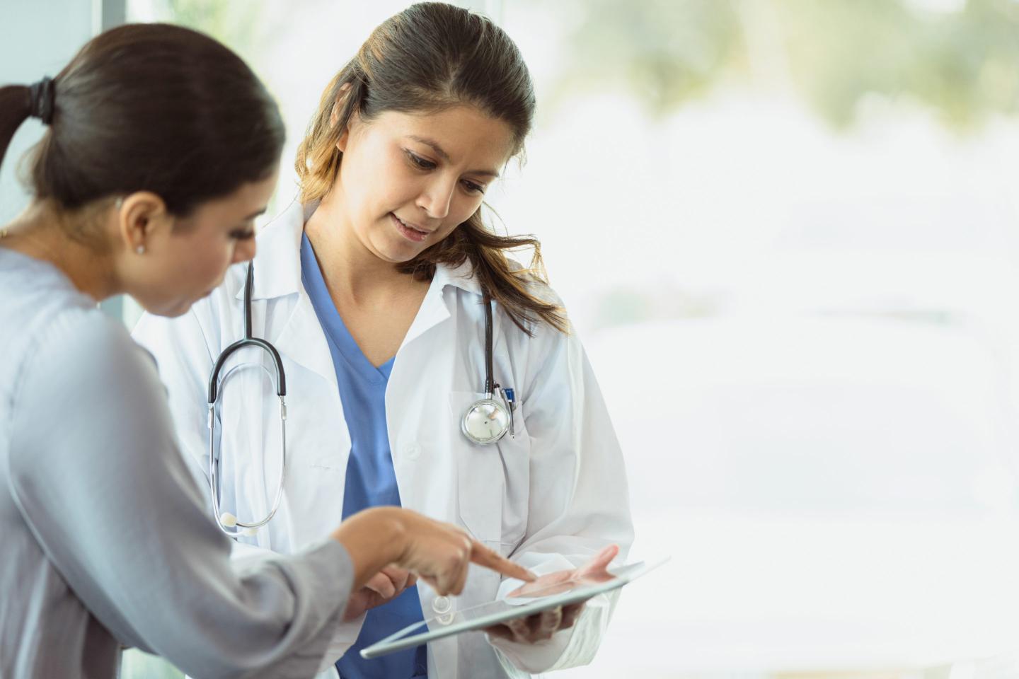 Doctor looking at tablet with patient