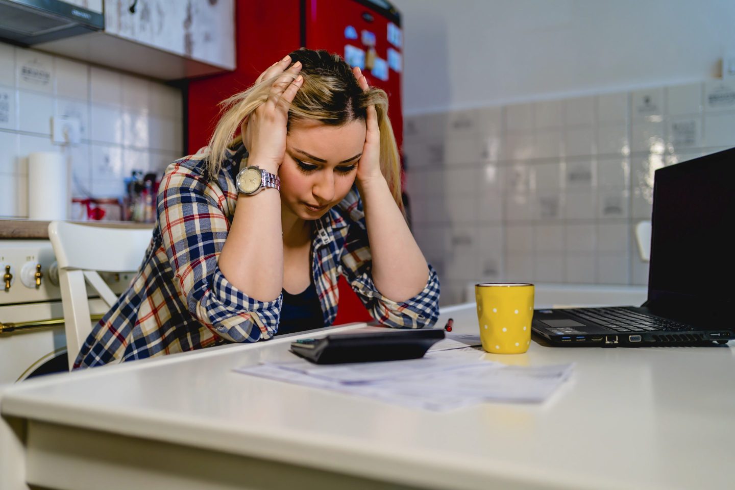 Young upset woman sitting at home, frustrated with family financial problems, paying bills taxes online on computer in the evening