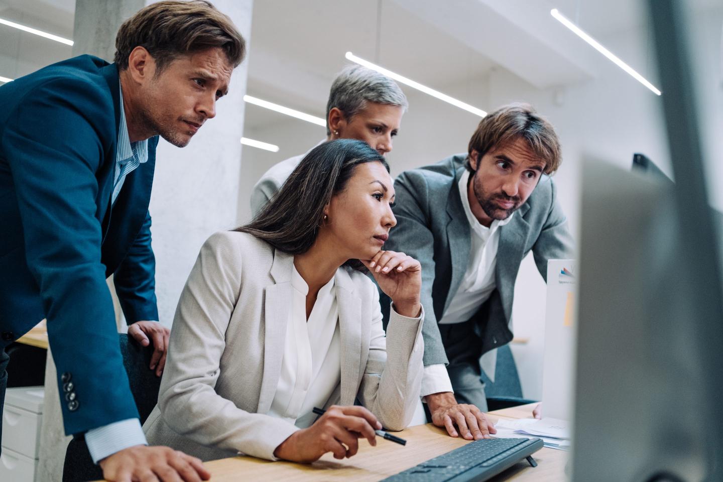 colleagues using computer together at work