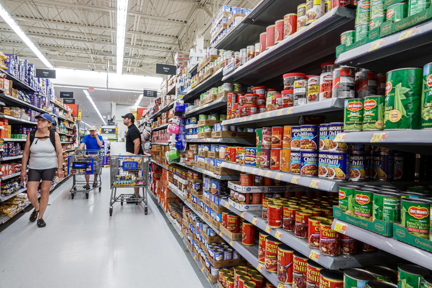 Del Monte, Armour and Hormel canned goods aisle with shoppers.