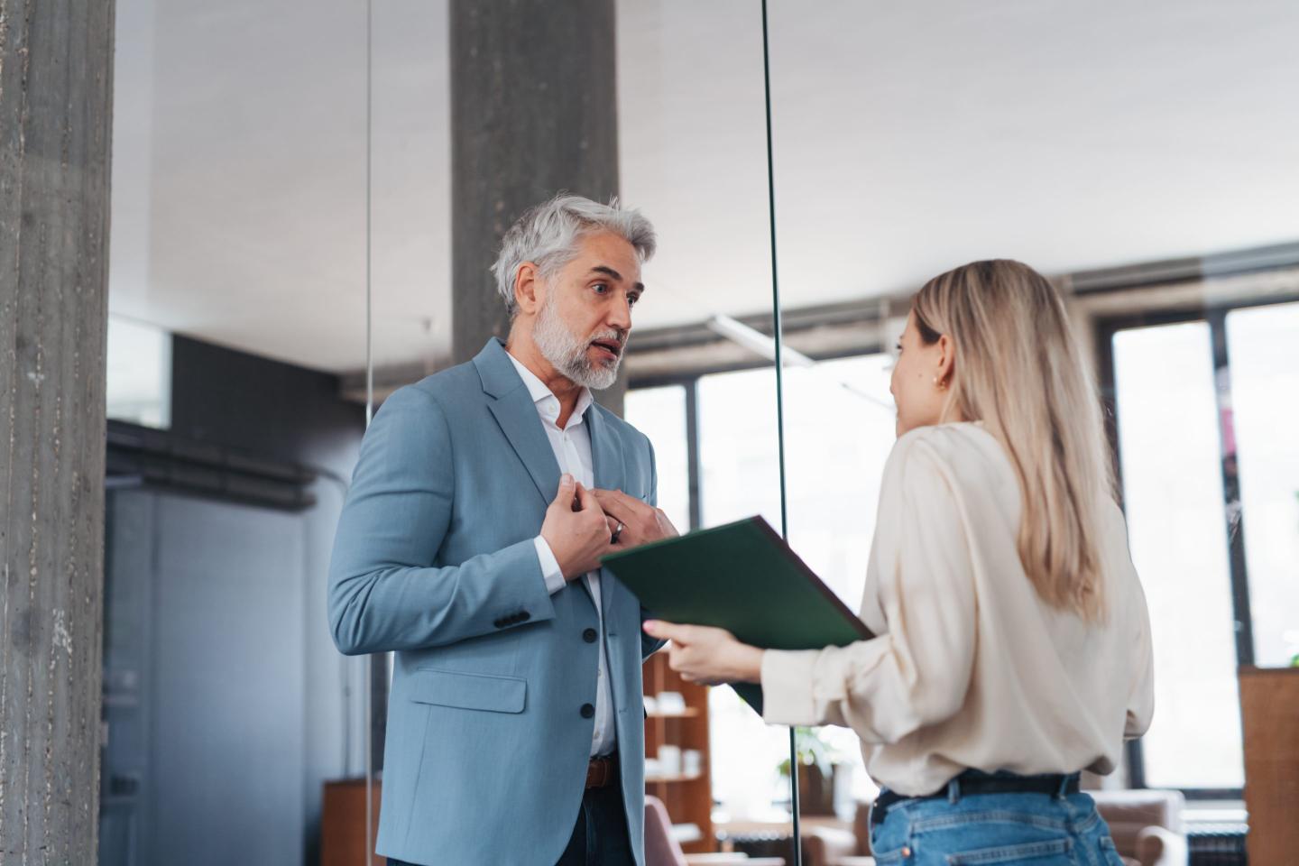 Man standing in front of woman scolding her in an office.