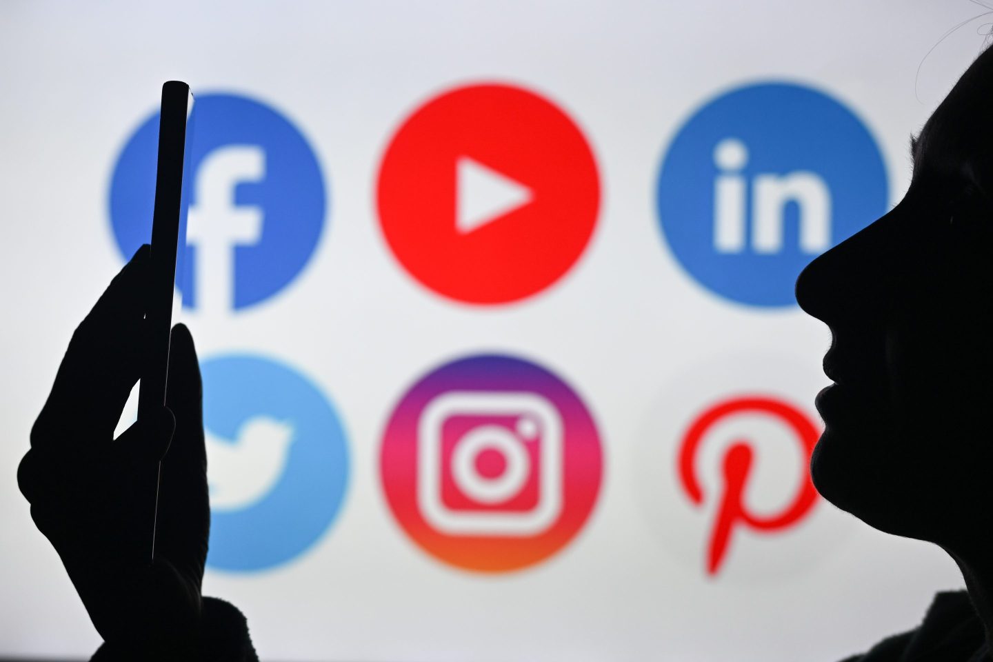 person using a phone with social media app icons in the background