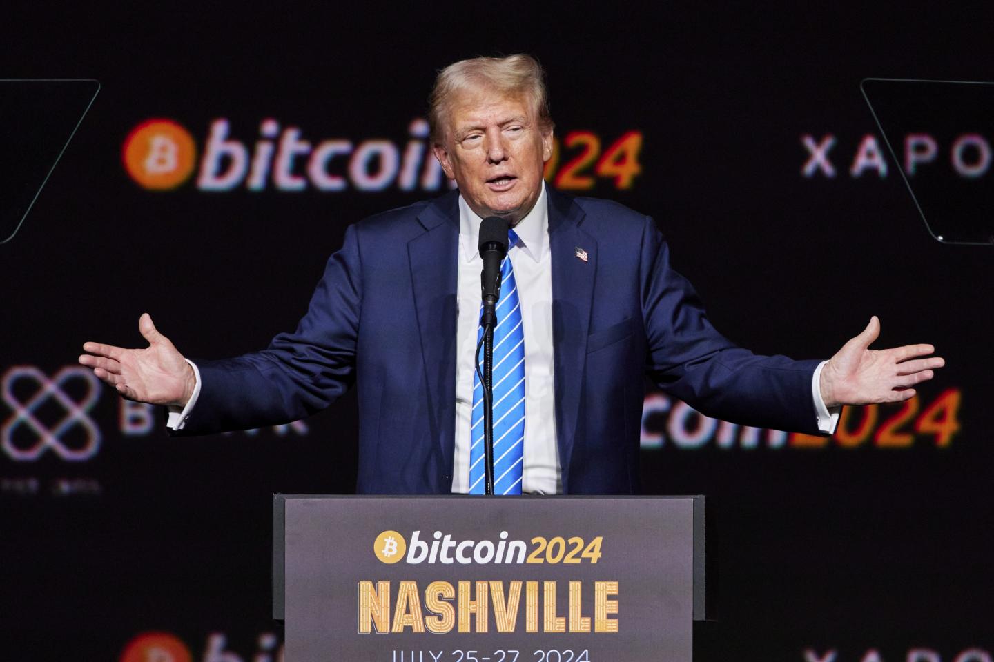President Donald Trump standing at a podium with his arms spread wide