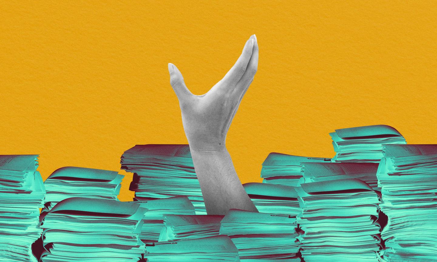 hand sticking out of mountain of paperwork