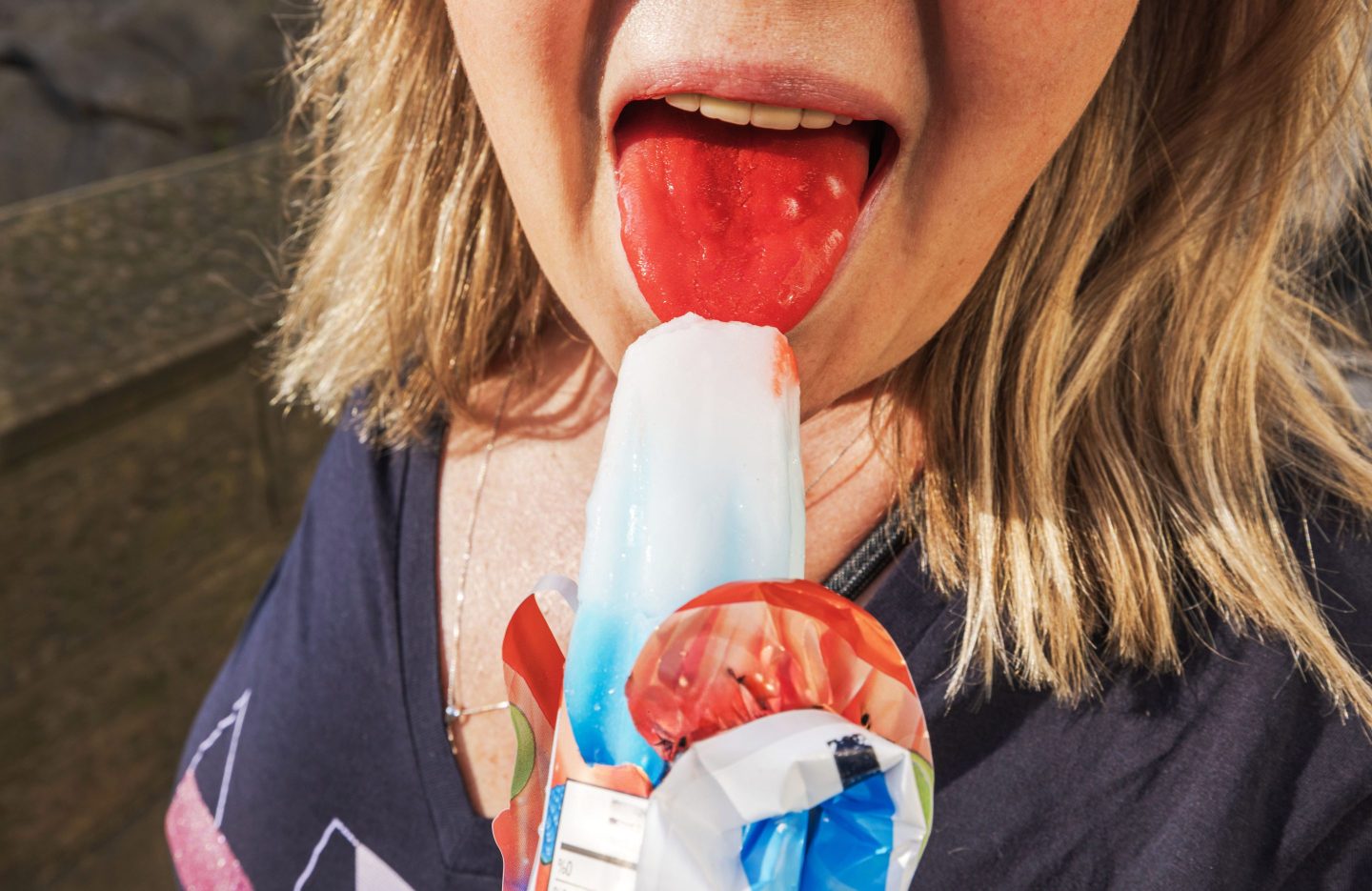 Girl with red tongue licking ice pop