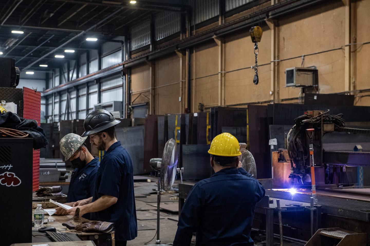 Workers look over paperwork and monitor a plasma torch at Central Steel Supply Company in Marlborough, Massachusetts on March 13, 2025.