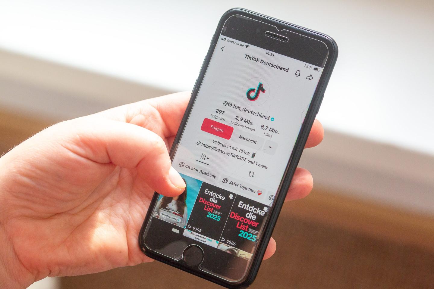 A user holds a smartphone with the TikTok app open.