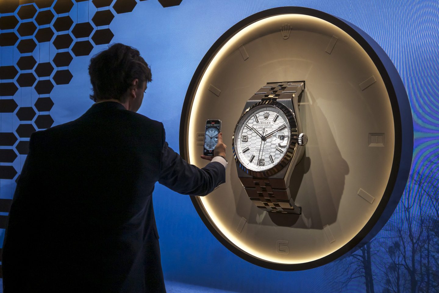 A man takes a picture of a giant model replica of a new Rolex land-dweller model