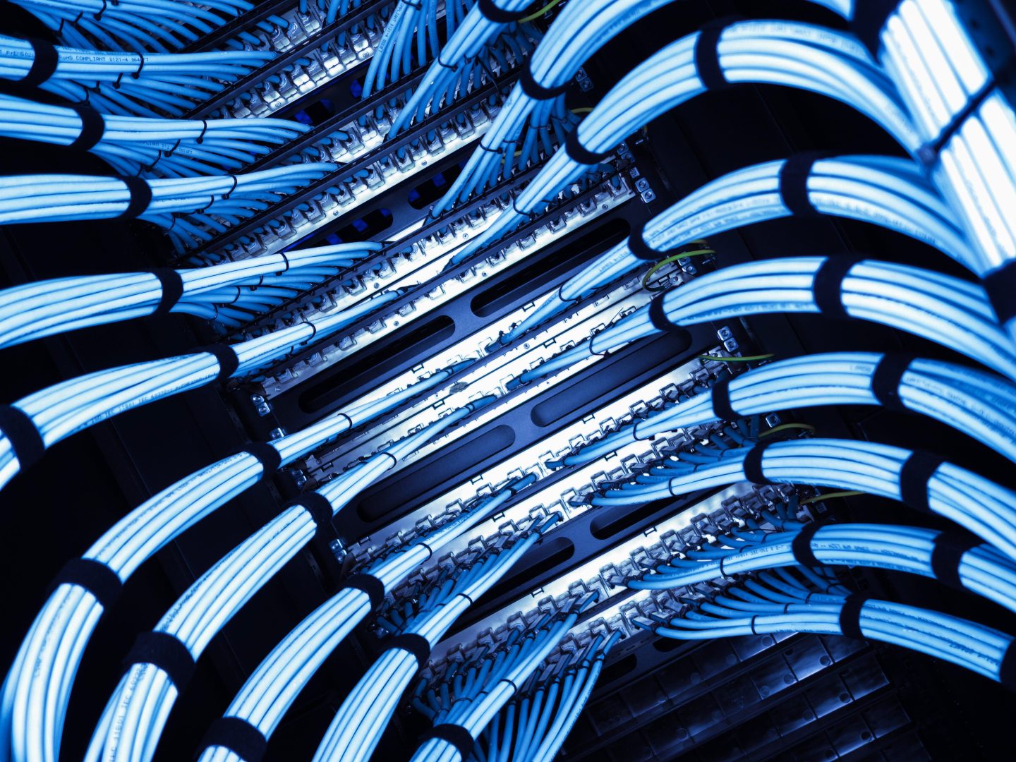 A vibrant view of blue cables organized within a data center, highlighting modern technology and efficient cable management in a server environment.