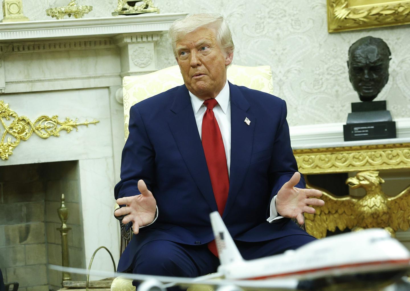 President Donald Trump at a press conference with his hands raised.