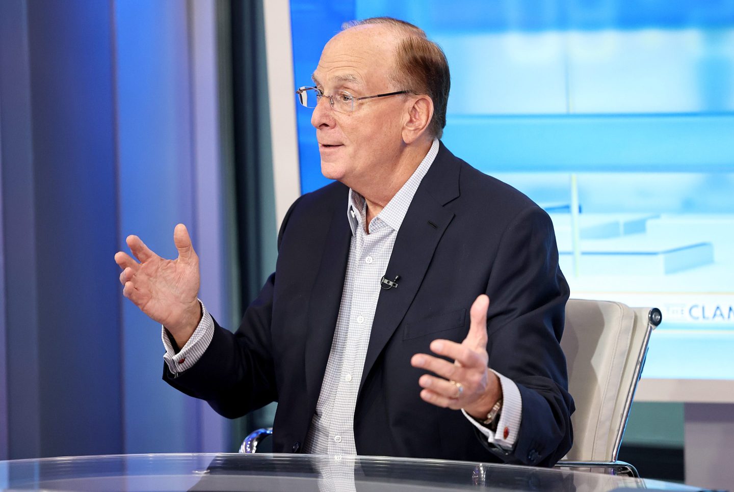 Larry Fink talks on a television set.