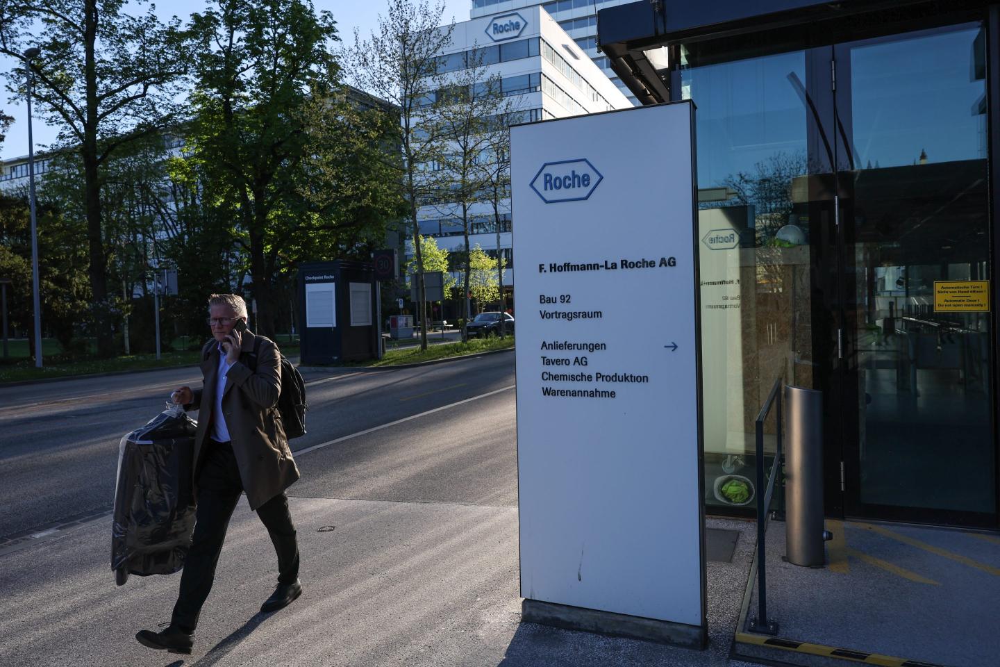 A man walks next to a sign for the Roche Holding AG headquarters on April 11, 2025 in Basel, Switzerland. Before US President Donald Trump postponed a range of imminent tariffs, Switzerland was facing a daunting 31% levy on most Swiss goods to imported to the United States, a higher rate than would have been imposed on European Union countries. Such a tariff would've been high damaging to iconic Swiss industries like chocolate and watchmaking. The reprieve will provide breathing room for Swiss officials looking to negotiate a deal with the US, although Swiss goods will still face a 10% tariff in the meantime, and the fate of a potential separate tariff on pharmaceuticals is unknown.