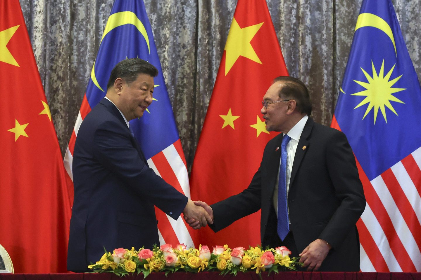 Chinese President Xi Jinping (left) and Malaysian Prime Minister Anwar Ibrahim shake hands at the end of an Exchange of Agreement session at the official residence of the prime minister in Putrajaya, outside Kuala Lumpur, on April 16, 2025.