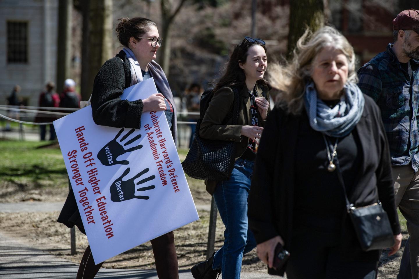 Protesters holding a sign walk across Harvard Yard.