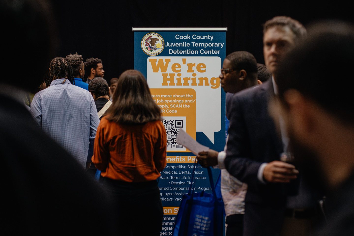"we're hiring" sign at a job fair
