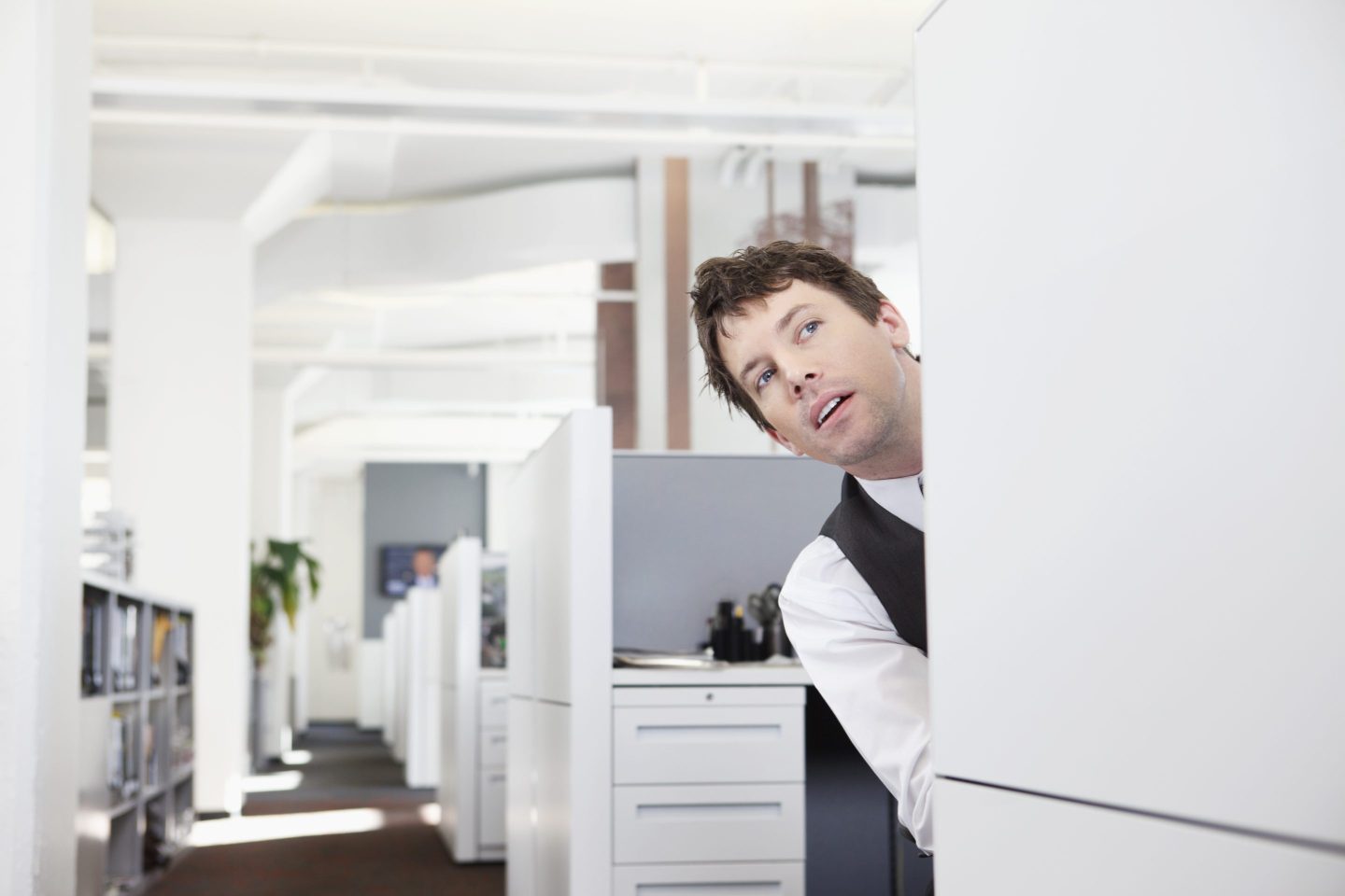 An office worker peeking around his cubicle and considering revenge RTO. 